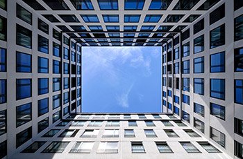 Low angle shot of an urban high building with glass windows and walls under a blue sky